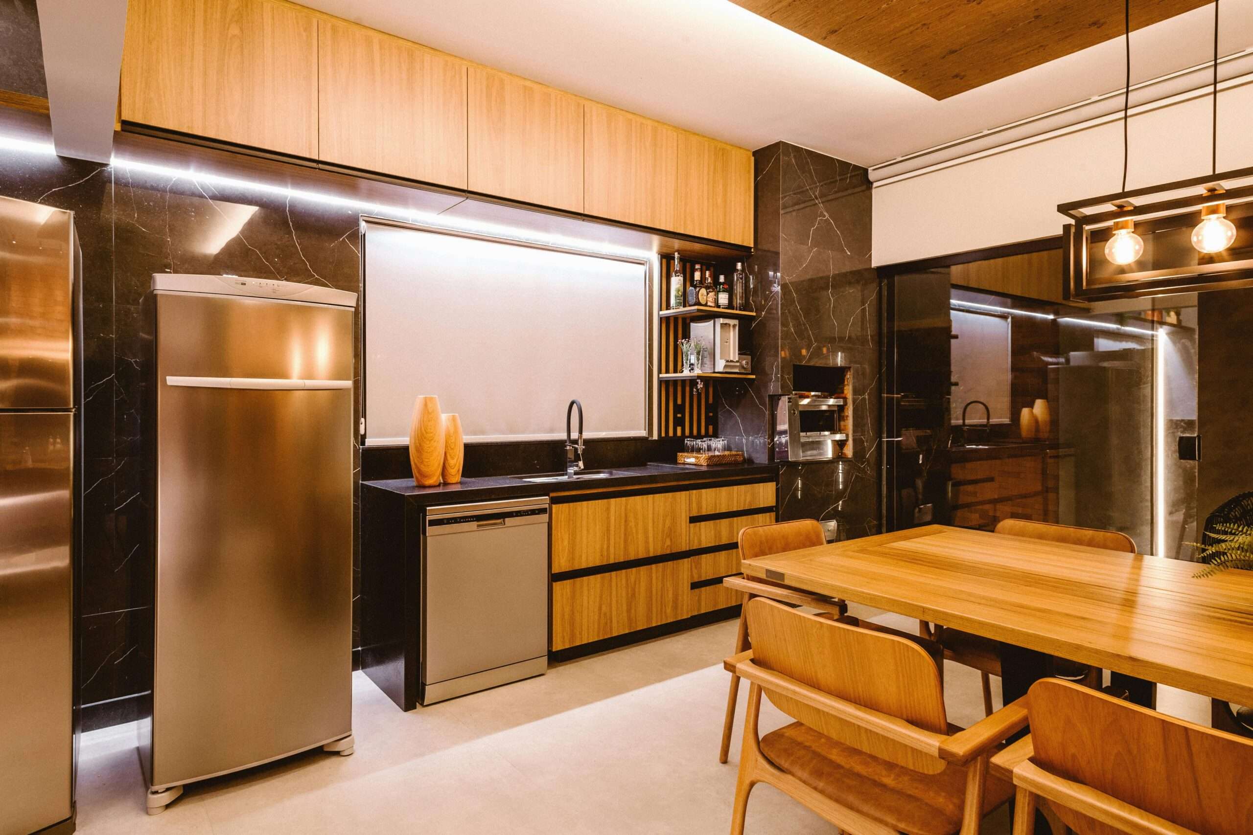 Stylish kitchen with wooden furniture, stainless appliances, and a modern pendant light.